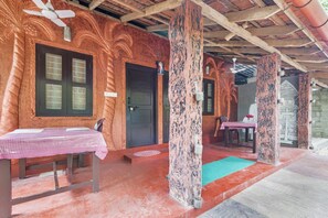 A rustic building with a checkered table and chairs, a door, and a wall with carved palm tree designs. - GuestHouser 1 BR Villa b529 (Cherthala)