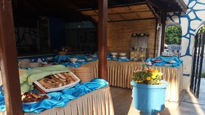 Disposição de buffet com diversos alimentos e um grande vaso azul com flores.