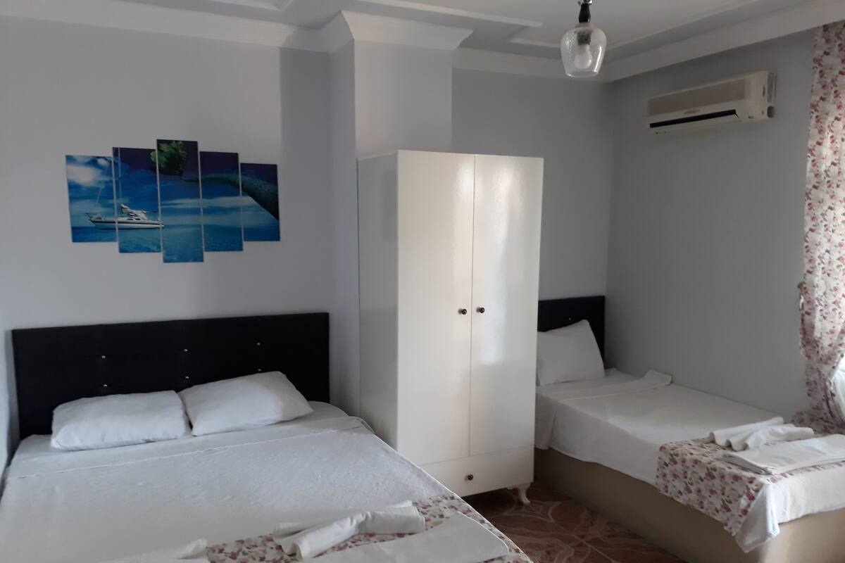 Hotellihuone, jossa on kaksi sänkyä, vaatekaappi ja kattotuuletin.