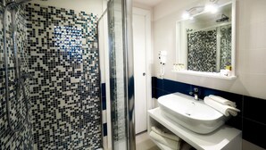 A bathroom with a shower, a sink, and a mirror.