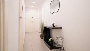 A hallway with a black console table, a mirror, and a chair.