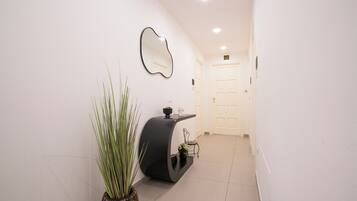 A hallway with a modern console table, a mirror, and a potted plant.