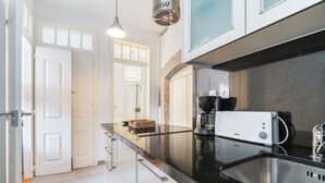 Una cocina moderna con encimera negra, armarios blancos y una cafetera.