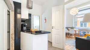 Una cocina compacta con una isla central, un área de comedor con mesa y sillas, y un espacio de estar con sofá.