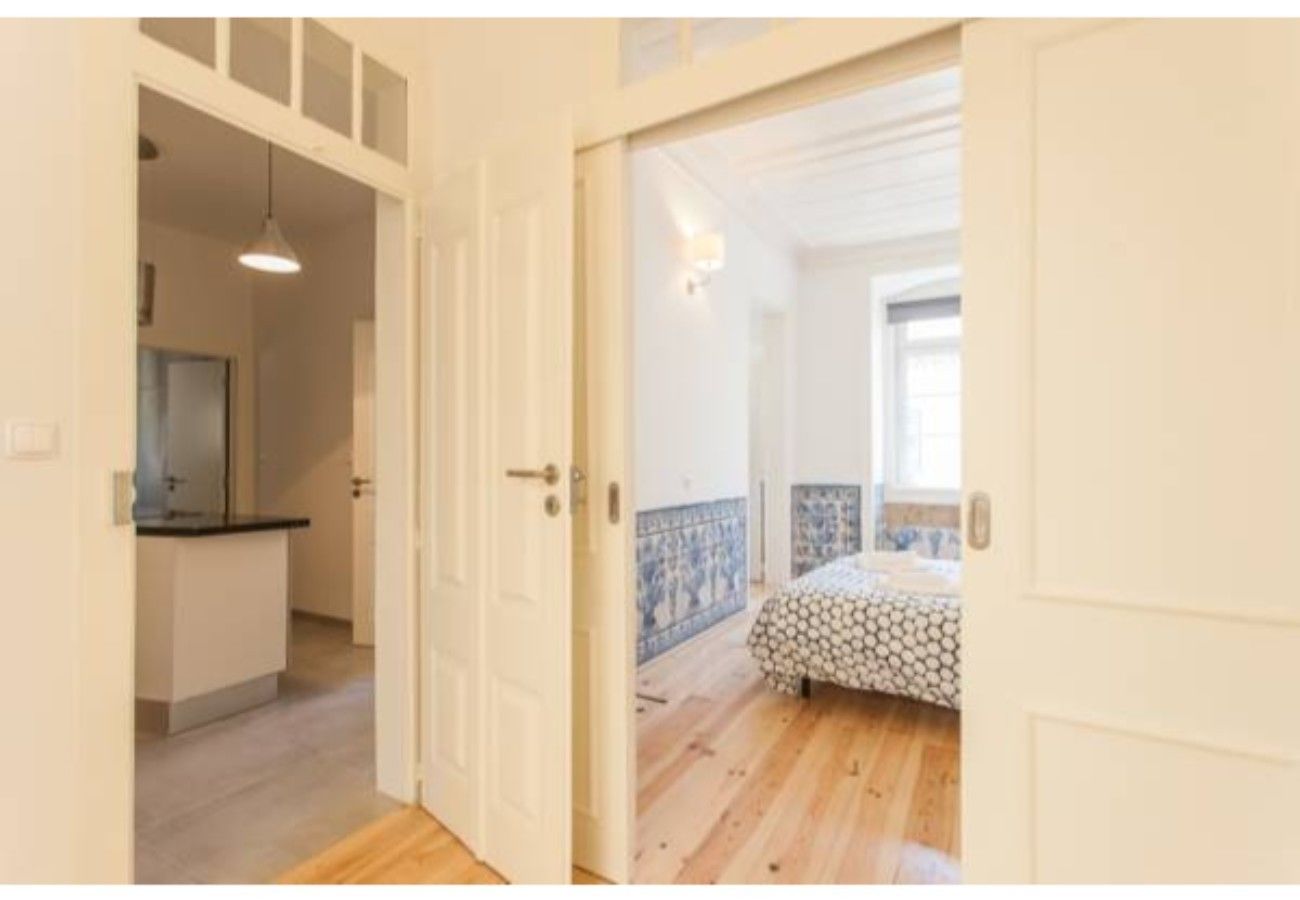A room with a bed, a small kitchenette, and a bathroom visible through an open door.