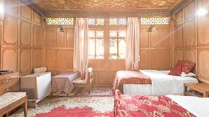 A traditional room with wooden paneling, two beds with red and white bedding, a small table, and a bench. - GuestHouser 3 BHK Houseboat d520 (Srinagar)