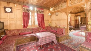 A traditional room with a sofa set, a table, and a television. - GuestHouser 3 BHK Houseboat d520 (Srinagar)