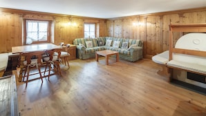 A cozy room with wooden walls and floors, a sofa set, a dining table with chairs, and a bunk bed. - Villa Lacedel (Cortina d'Ampezzo)