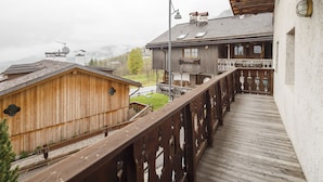 A wooden deck with a railing, a building with a balcony, and a view of a mountain in the background. - Villa Lacedel (Cortina d'Ampezzo)