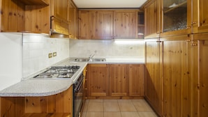 A kitchen with wooden cabinets, a granite countertop, a stainless steel sink, and a gas stove. - Villa Lacedel (Cortina d'Ampezzo)