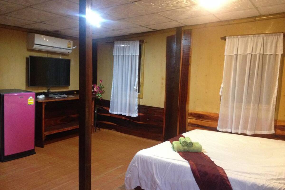 A hotel room with a bed, a desk, a television, and a refrigerator.