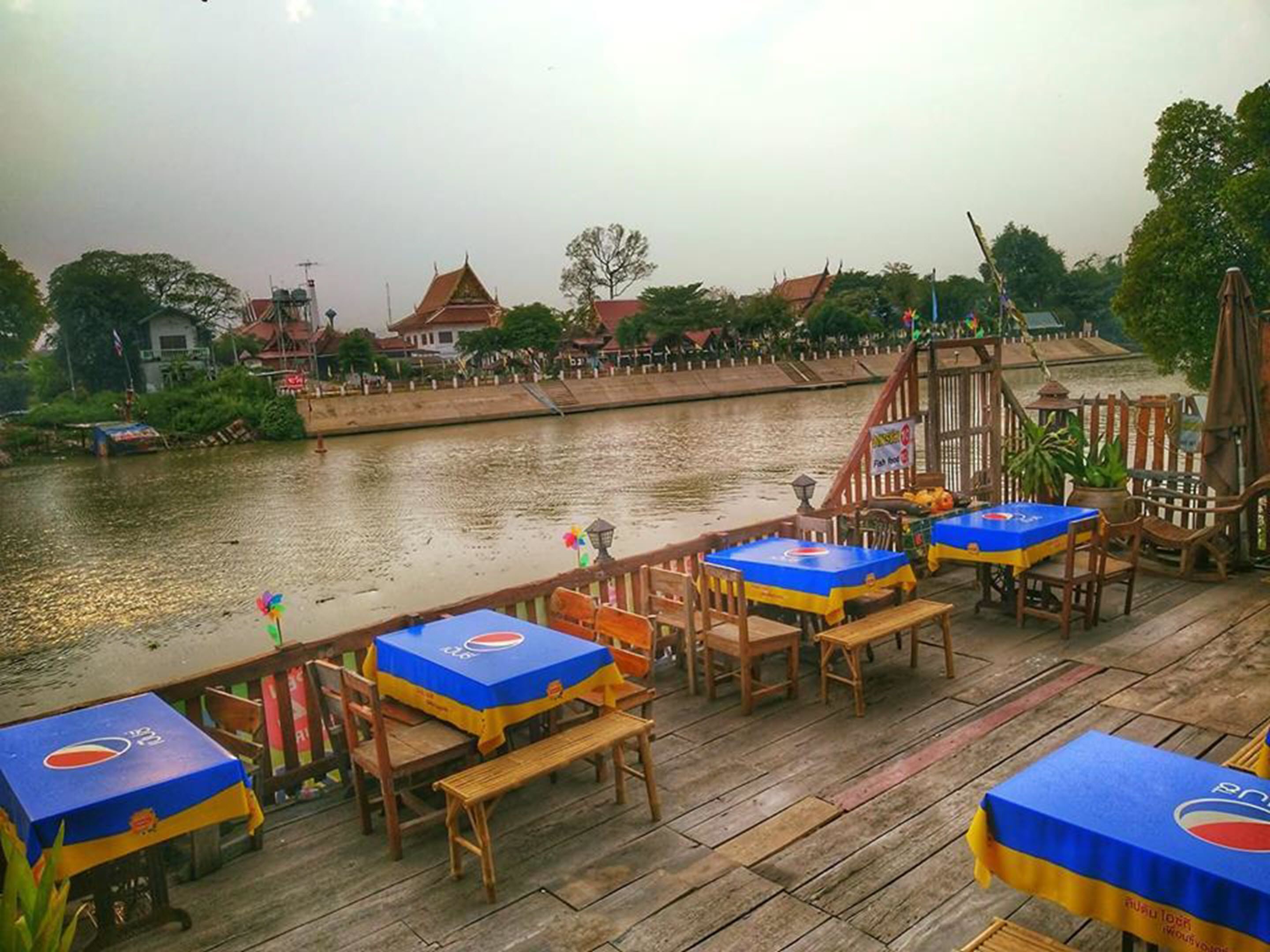 A riverside restaurant with outdoor seating and a view of the river.