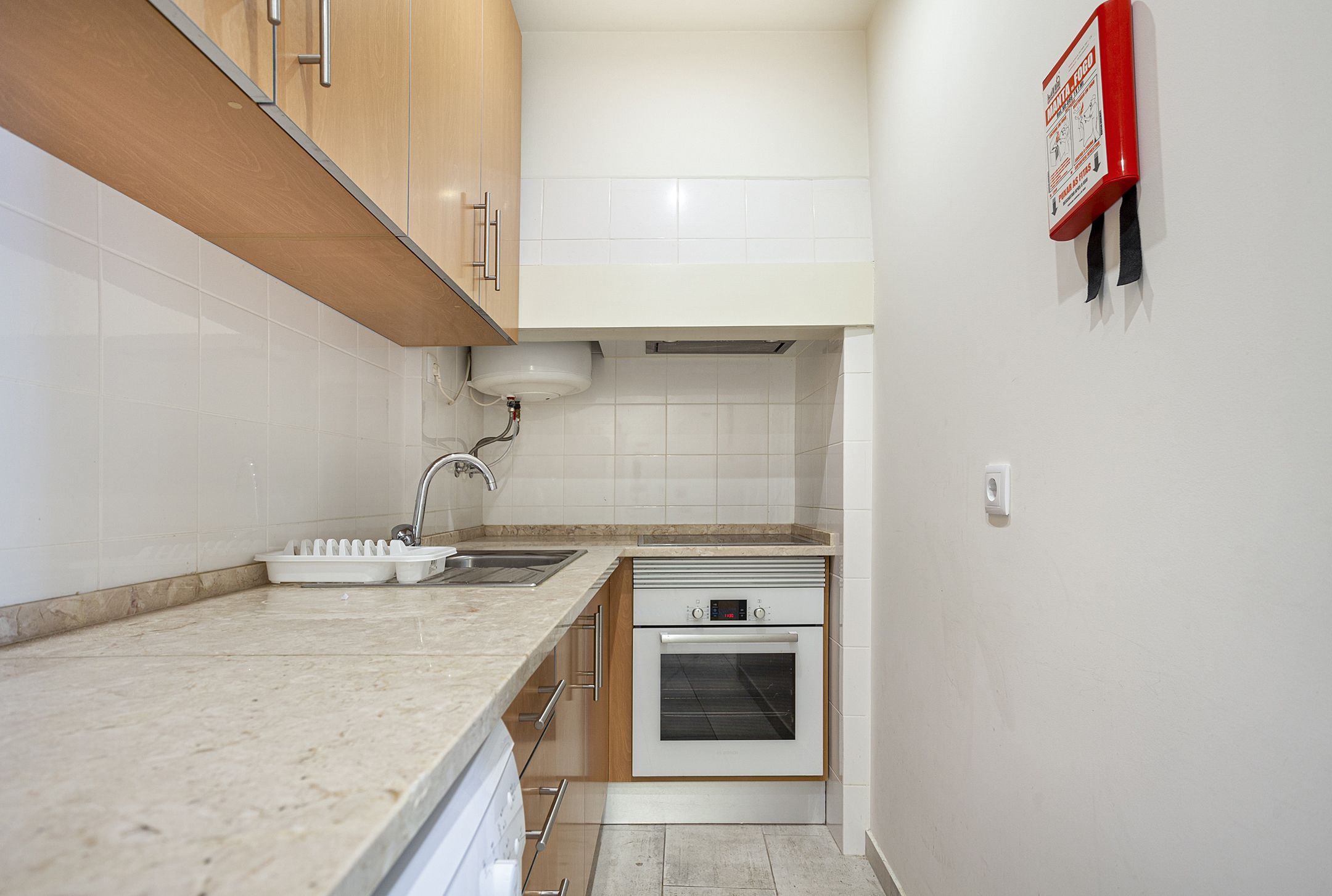 A compact kitchen with wooden cabinets, a built-in oven, and a sink.