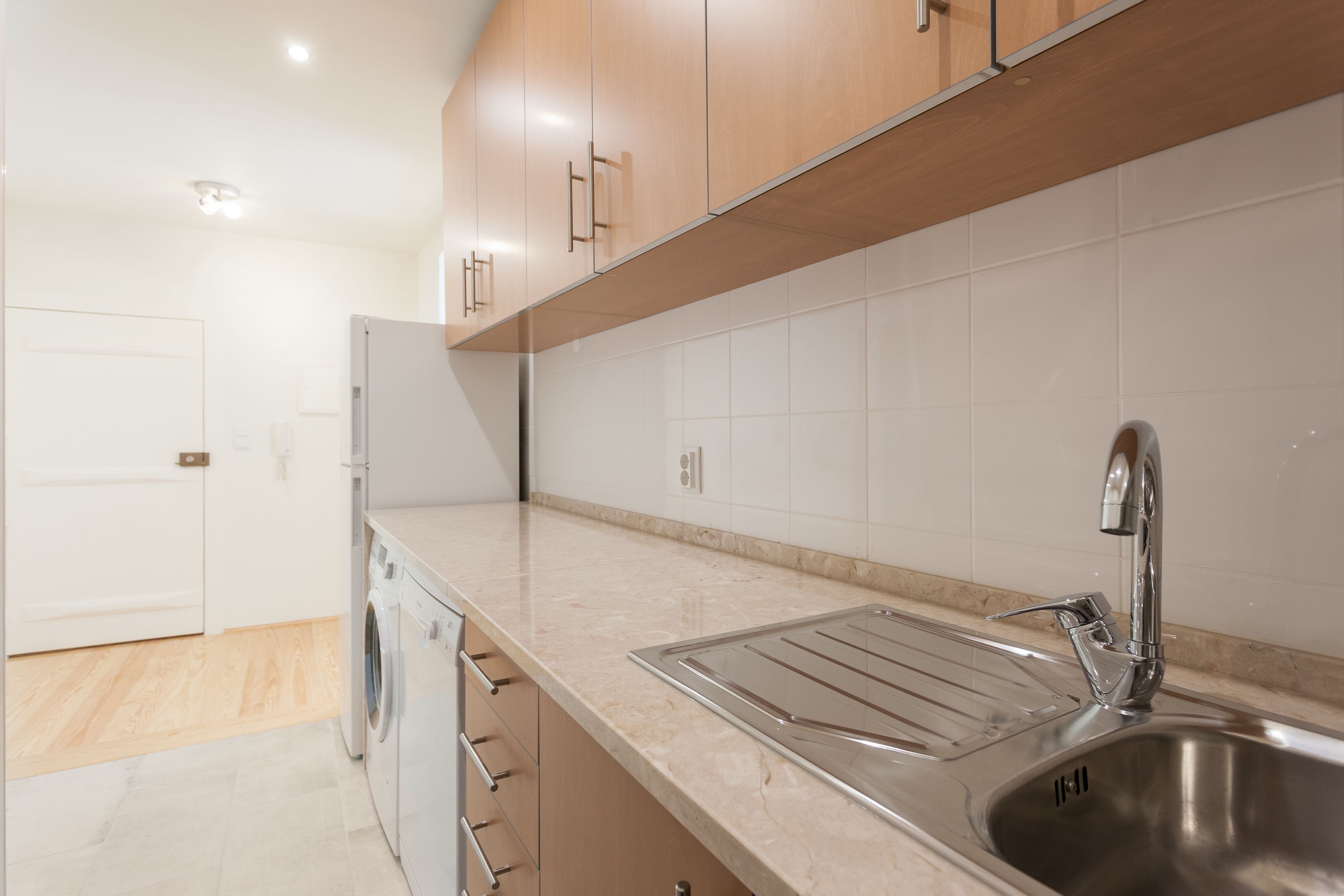 A modern kitchen with stainless steel appliances, a sink, and wooden cabinets.
