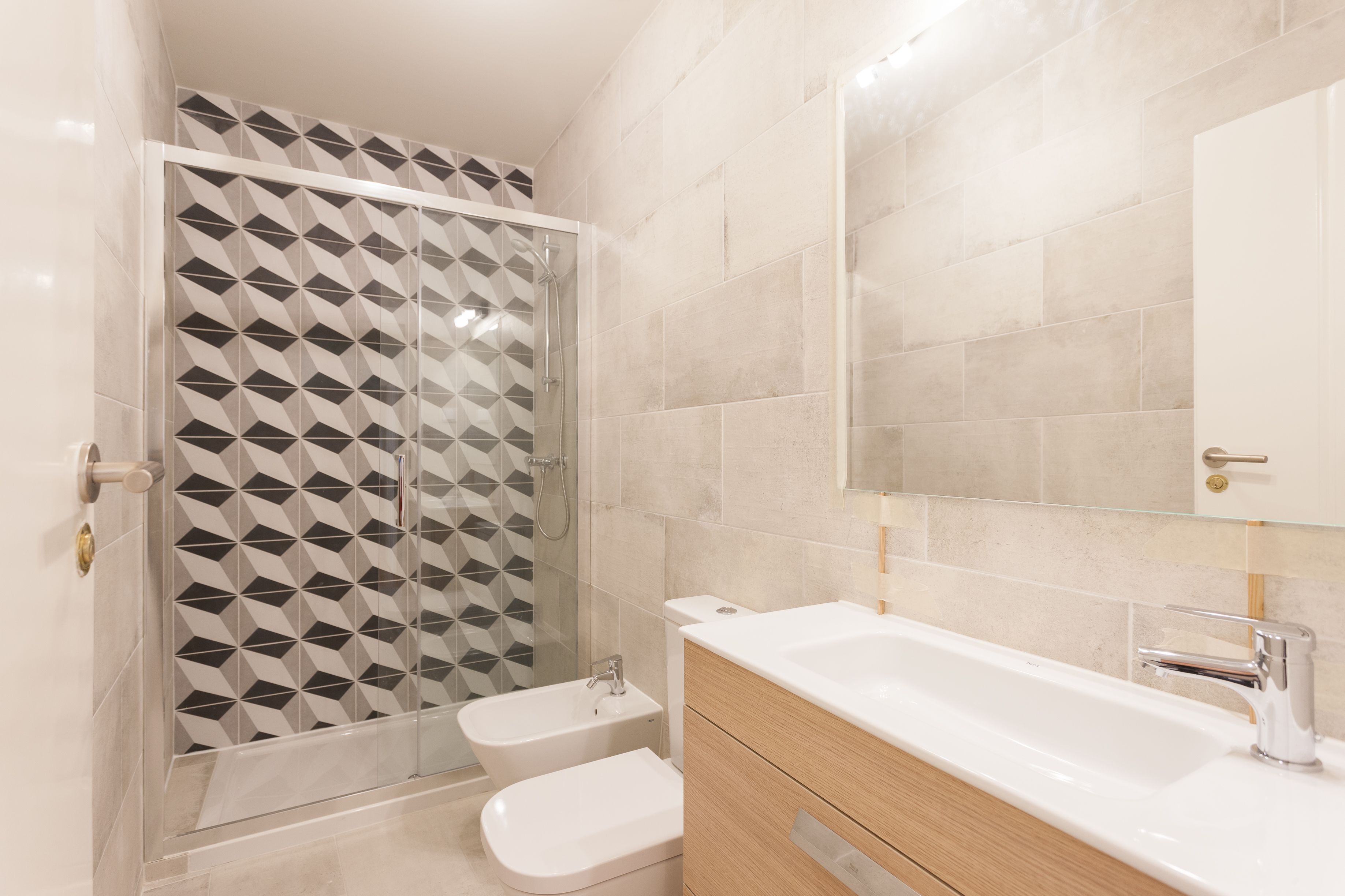 A modern bathroom with a shower enclosure, a sink, and a mirror.