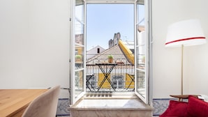 A room with a view of a yellow building with a tiled roof, a balcony with a table and chairs, and a red lamp. - Gonzalo's Guest Apartments - Downtown Historic Flats III (Lisbon)