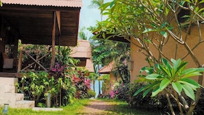 A garden pathway leading to a building with a corrugated metal roof and a wooden structure. - Bangrak Pier Bungalow (Koh Samui)