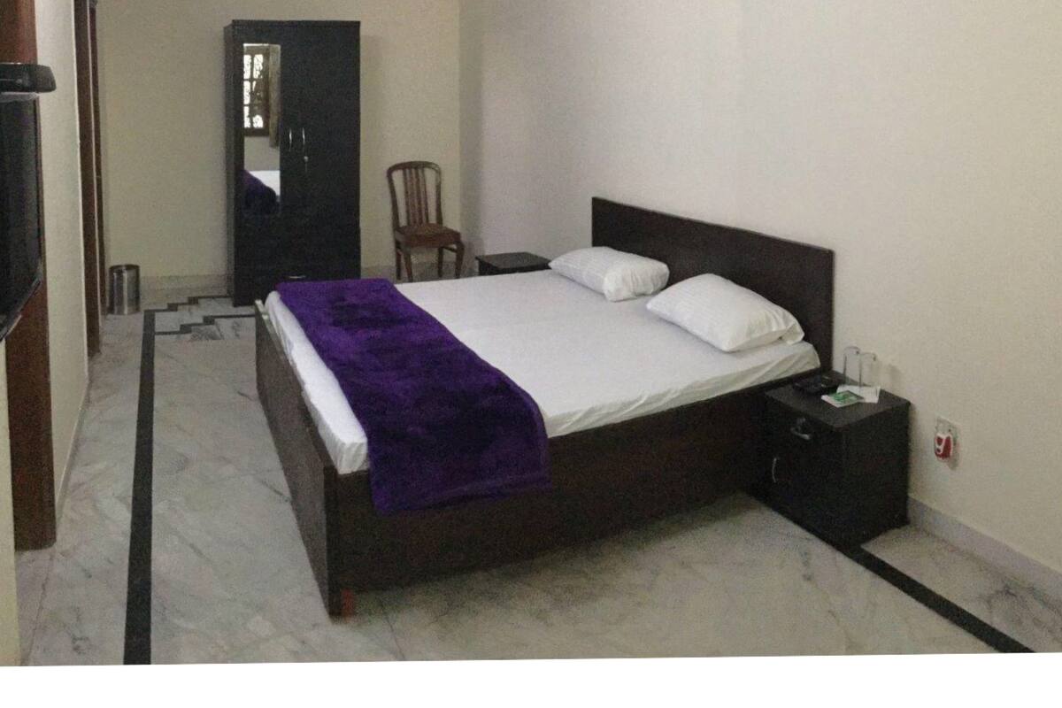 Een slaapkamer met een bed, nachtkastje, stoel, kledingkast en plafondventilator.