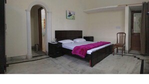 Un dormitorio con cama, mesita de noche, silla y un arco de entrada.