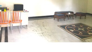 Una habitación con ventilador de techo, un cuadro en la pared, un sofá, una mesa de centro y un comedor con sillas y una mesa.