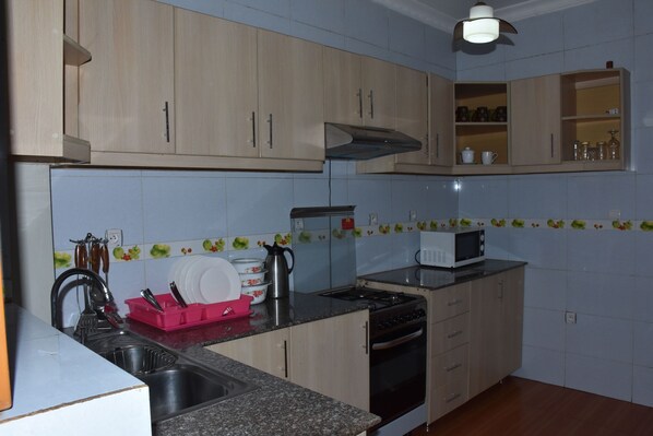 A kitchen with wooden cabinets, a microwave, a stove, and a sink.