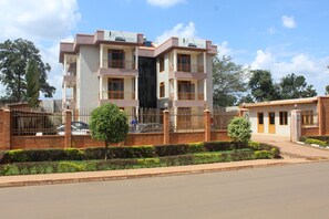 A multi-story building with balconies, a gated entrance, and a landscaped front yard.