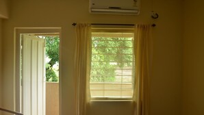 Una habitación con ventana, unidad de aire acondicionado y puerta que da al exterior.
