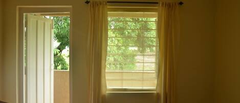 A room with a window, an air conditioning unit, and a door leading outside.