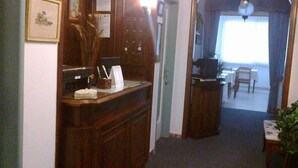 Un pasillo con un escritorio de madera, una planta y un comedor con mesa y sillas.