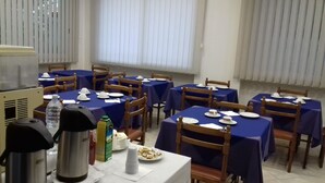 Un comedor con varias mesas cubiertas con manteles azules, sillas de madera y platos blancos listos para una comida.