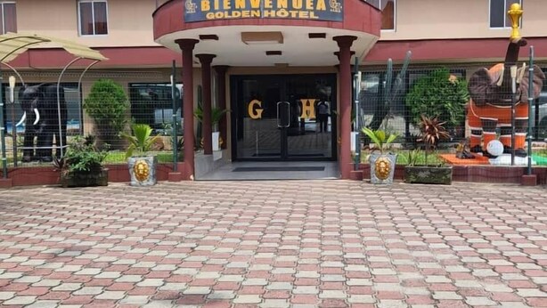 The entrance of the Golden Hotel with a tiled pavement and multiple flags. - Golden Hôtel (Abidjan)