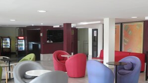 A modern lobby with colorful seating, a reception desk, and vending machines. - Golden Hôtel (Abidjan)