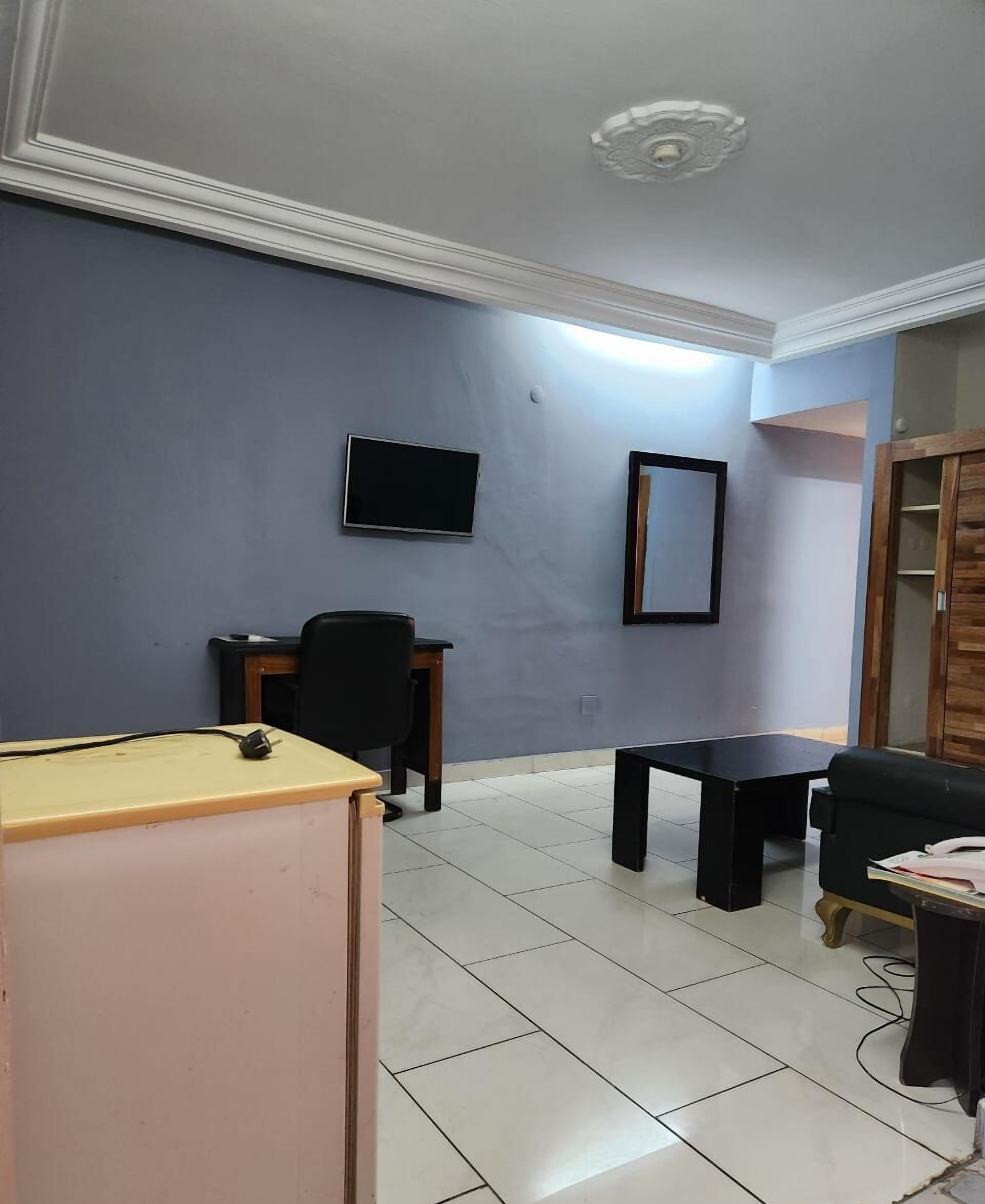 Une pièce comprenant un bureau, une chaise et un téléviseur fixé au mur.