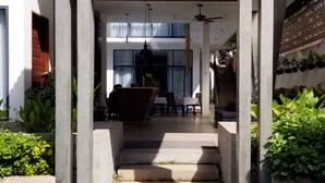 A modern building with a covered entrance, concrete pillars, a staircase, and a dining area with outdoor seating. - Angkor Siesta Villa (Siem Reap)