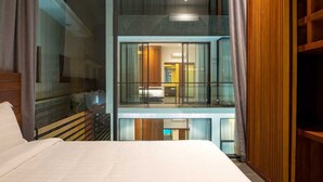 A hotel room with a large bed, a view of the interior through a glass partition, and a balcony with wooden railings. - Angkor Siesta Villa (Siem Reap)