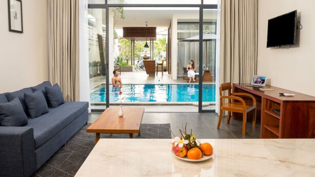 A modern living room with a pool view, a sofa, a dining table, and a TV. - Angkor Siesta Villa (Siem Reap)