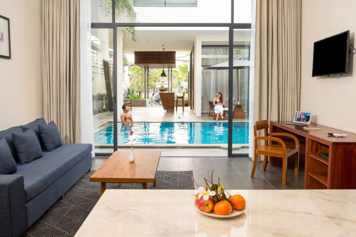 A modern living room with a pool view, a sofa, a dining table, and a TV.