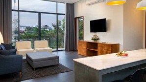 A modern living room with a sofa, a grey ottoman, a wooden cabinet, and a TV mounted on the wall. - Angkor Siesta Villa (Siem Reap)