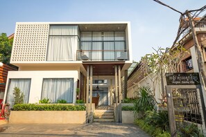 Eine moderne Villa mit einem Balkon, einer Treppe zum Eingang und einem Schild mit der Aufschrift 'Angkor Siesta Villa'.