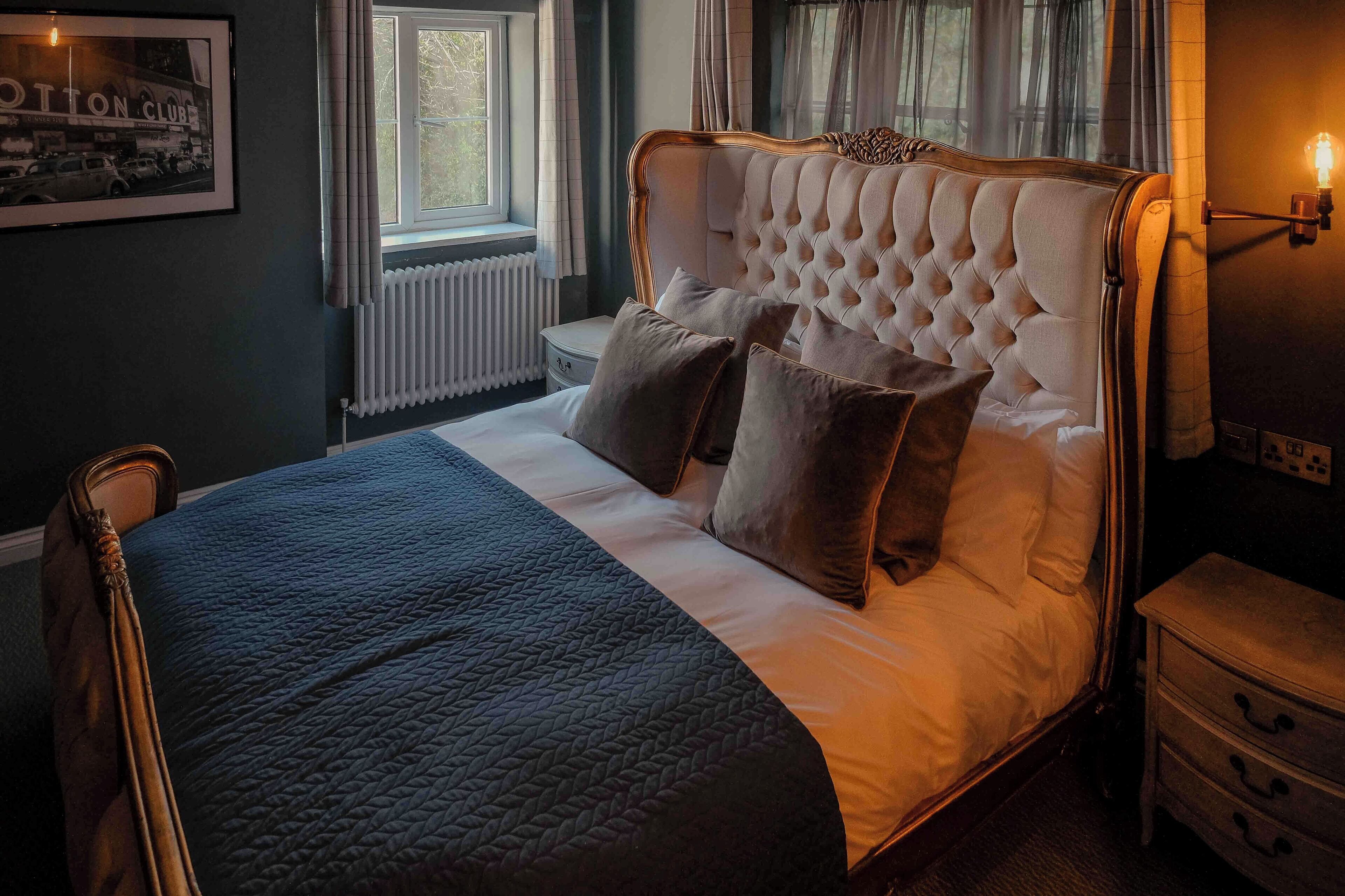 A neatly made bed with a tufted headboard, a bedside table, and a nightstand.