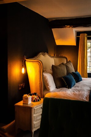 A bedroom with a bed, bedside lamp, nightstand, and a window with curtains.