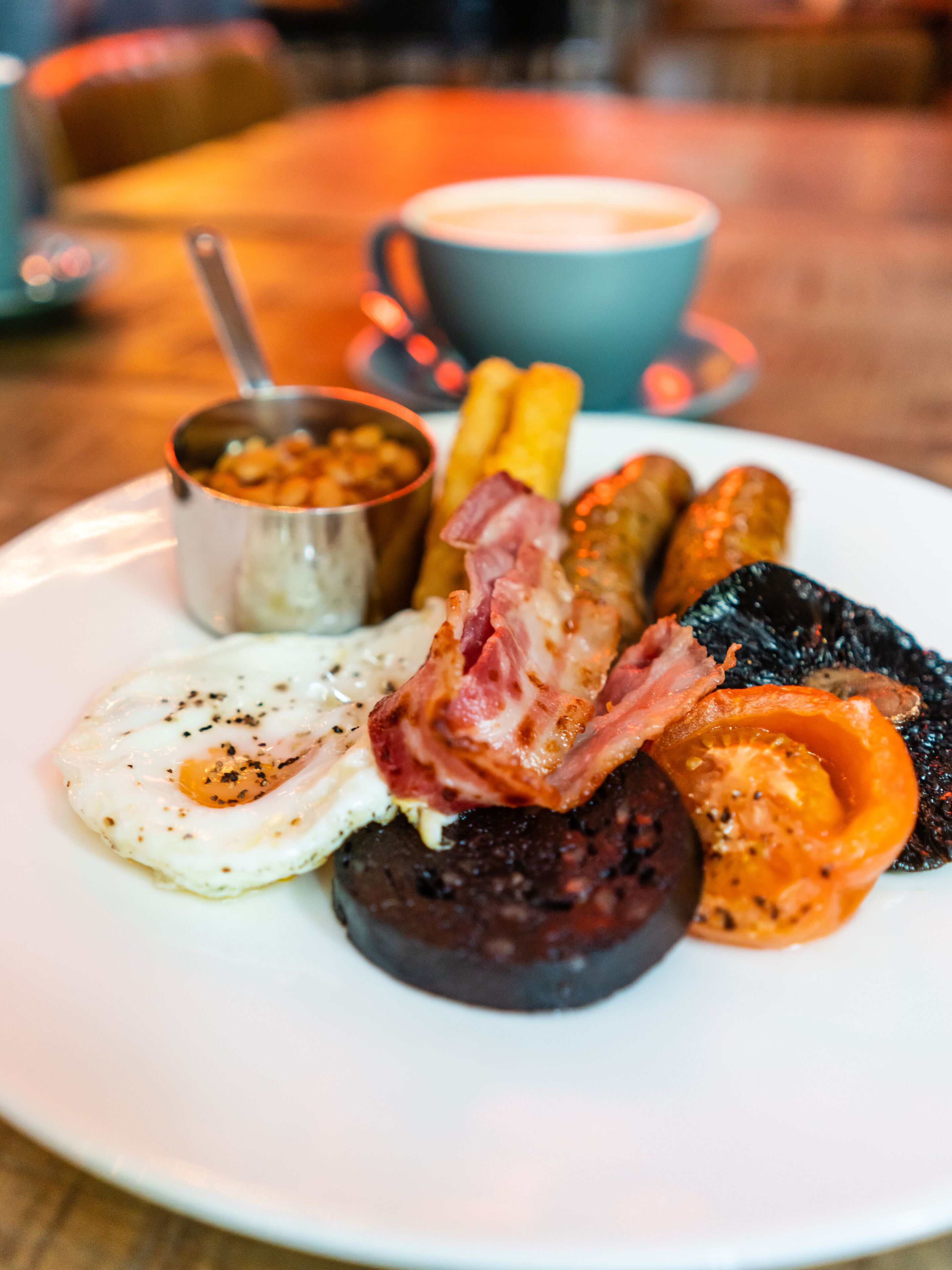 A plate of breakfast food including eggs, bacon, sausages, and tomatoes.