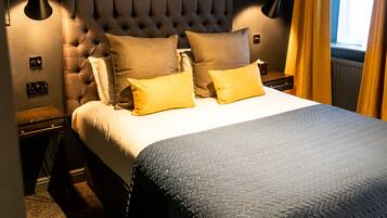A bedroom with a tufted headboard, a bed with a quilted cover, two bedside lamps, and a window with curtains.
