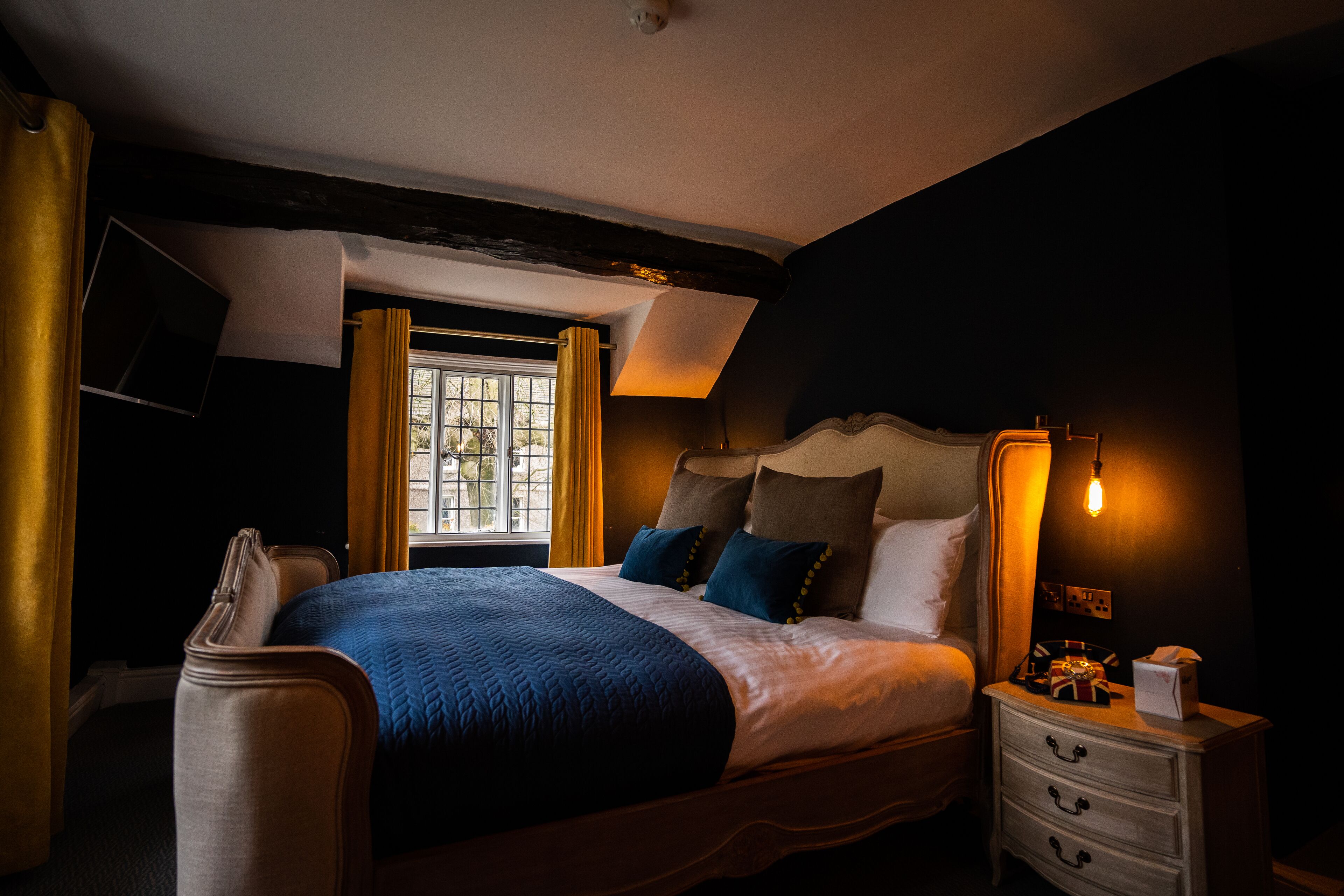A bedroom with a bed, bedside table, and a window with curtains.