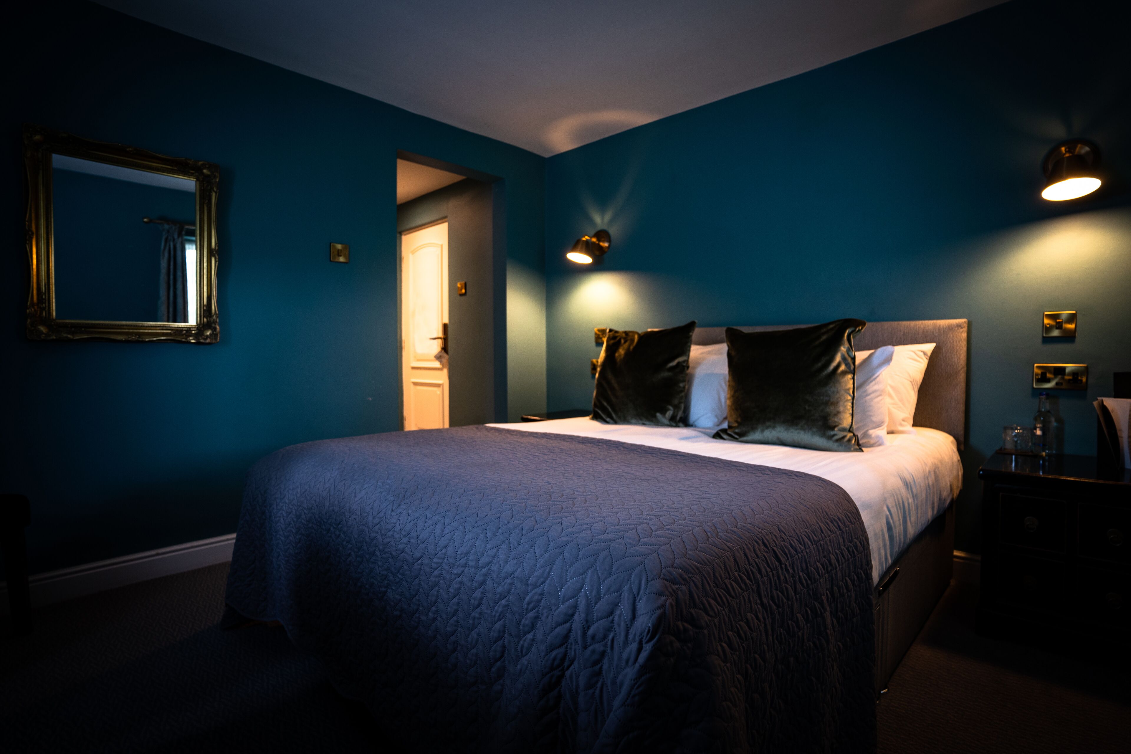 Ein Schlafzimmer mit einem großen Bett, einem Spiegel und Nachttischlampen.