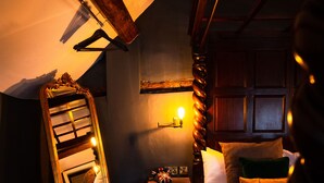 A bedroom with a sloped ceiling, a wooden ladder, a bedside table with a lamp, and a bed with pillows. - The Bridge (Macclesfield)