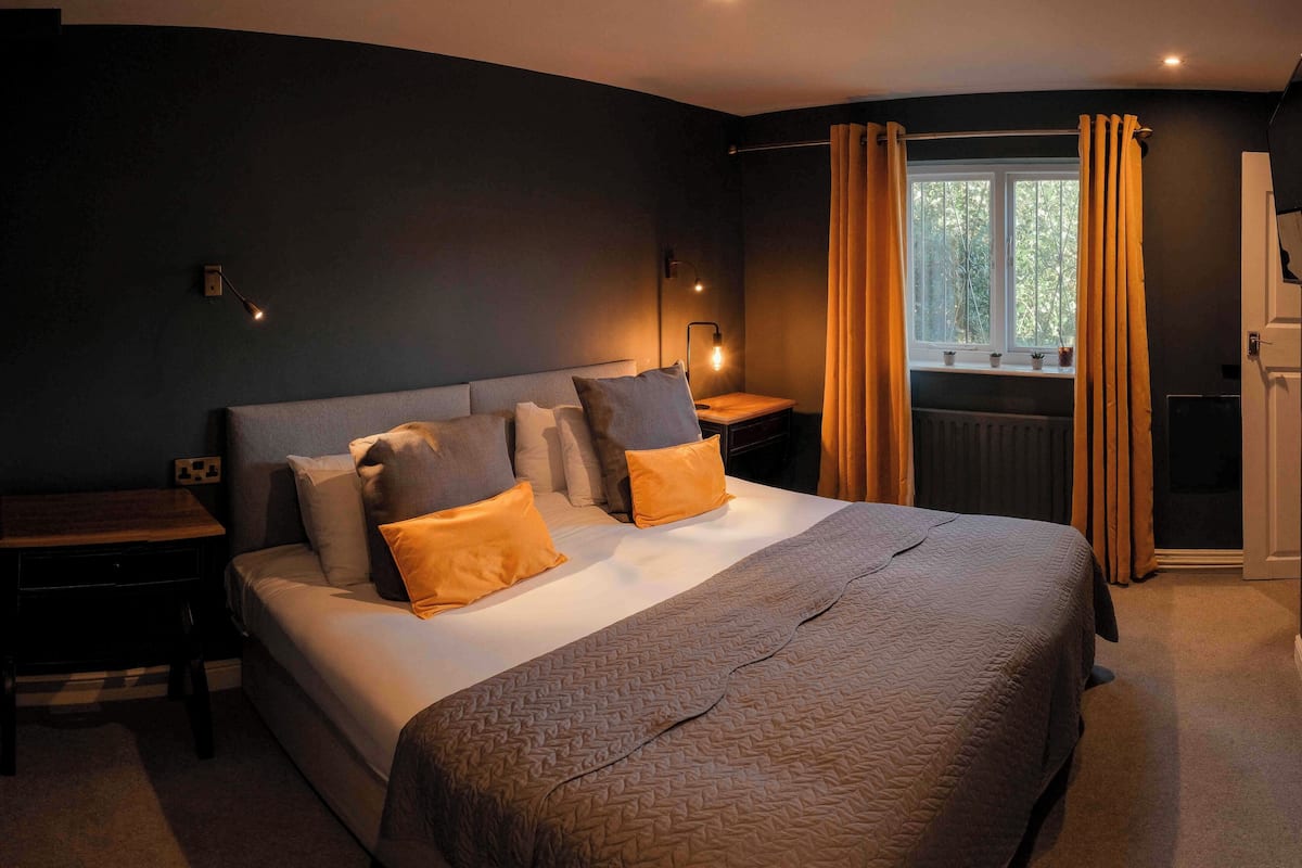 A neatly made bed with a patterned bedspread, two bedside tables with lamps, and a window with curtains.