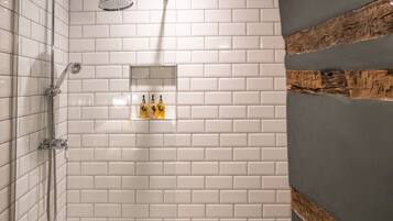 Un área de ducha moderna con azulejos blancos, puerta de vidrio y una pared de acento de madera.