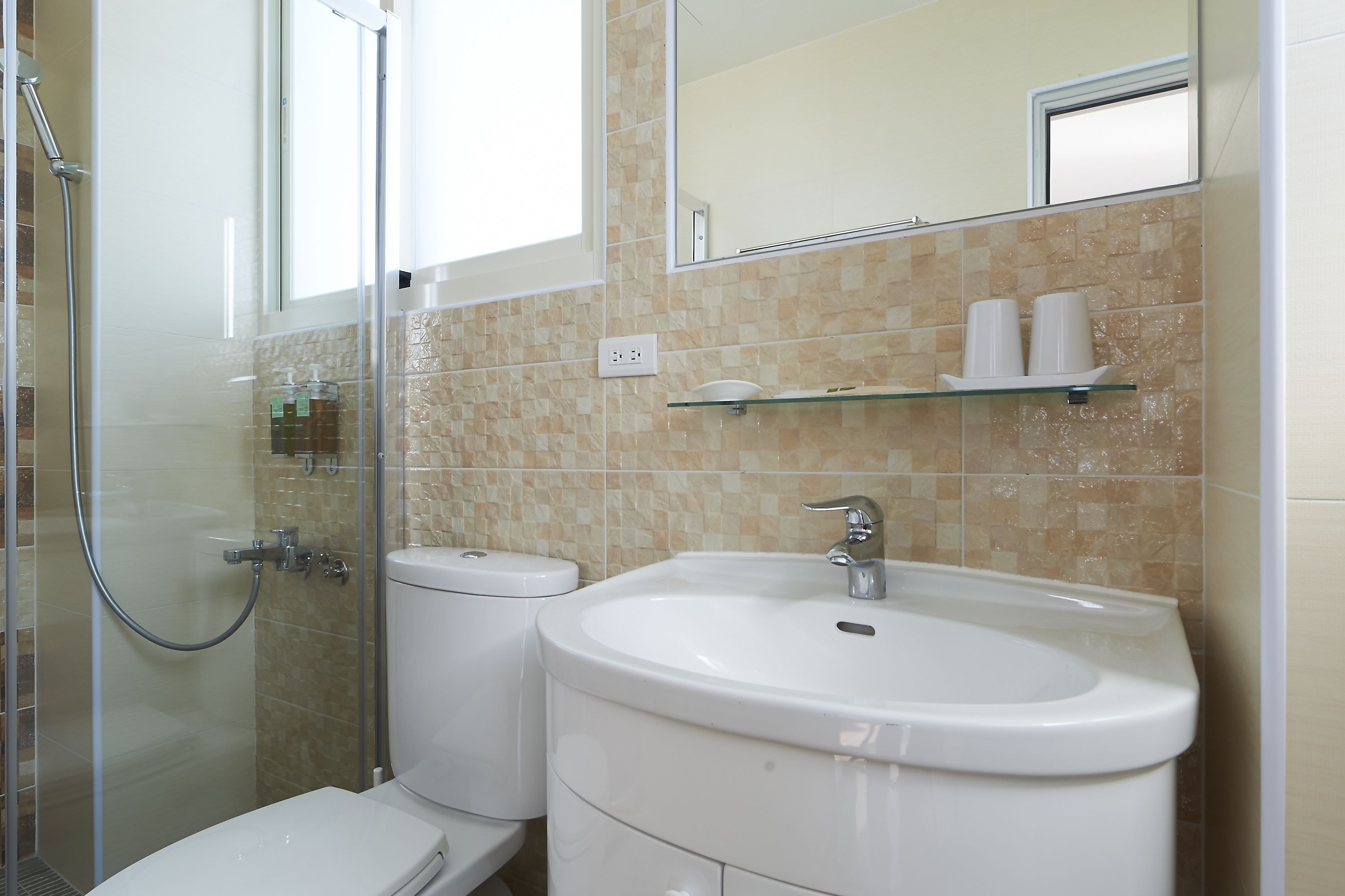 A bathroom with a glass shower enclosure, a white toilet, and a sink with a mirror above it.