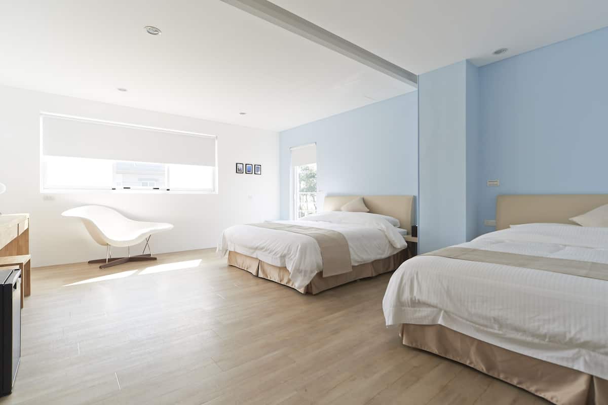 A modern hotel room with two beds, a desk, and a chair.